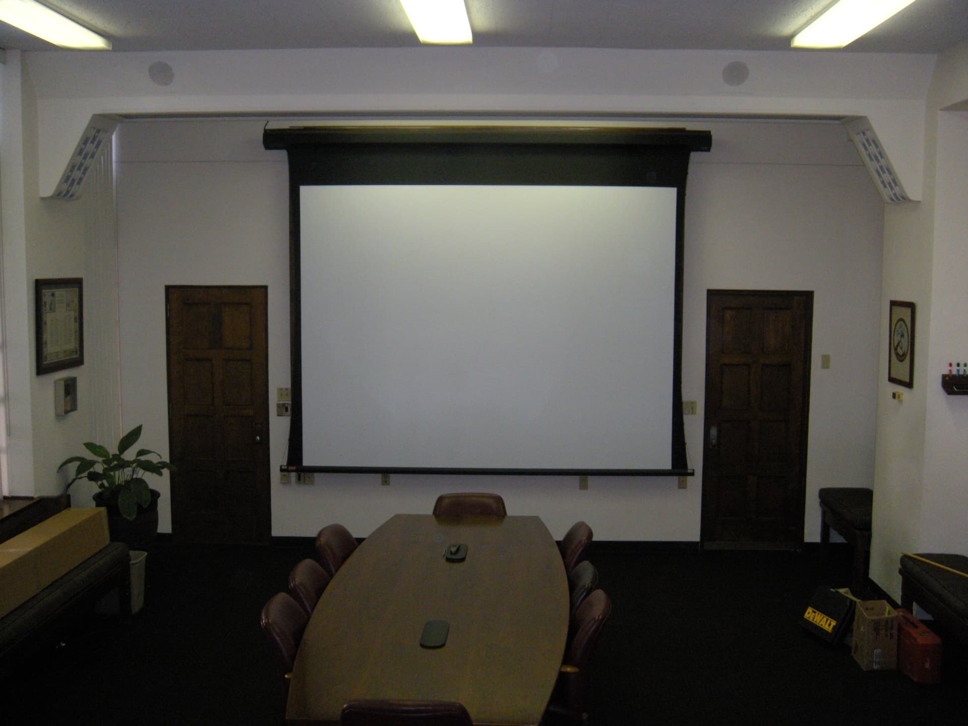 Conference room audio-visual installation featuring a motorized projection screen and integrated presentation system.