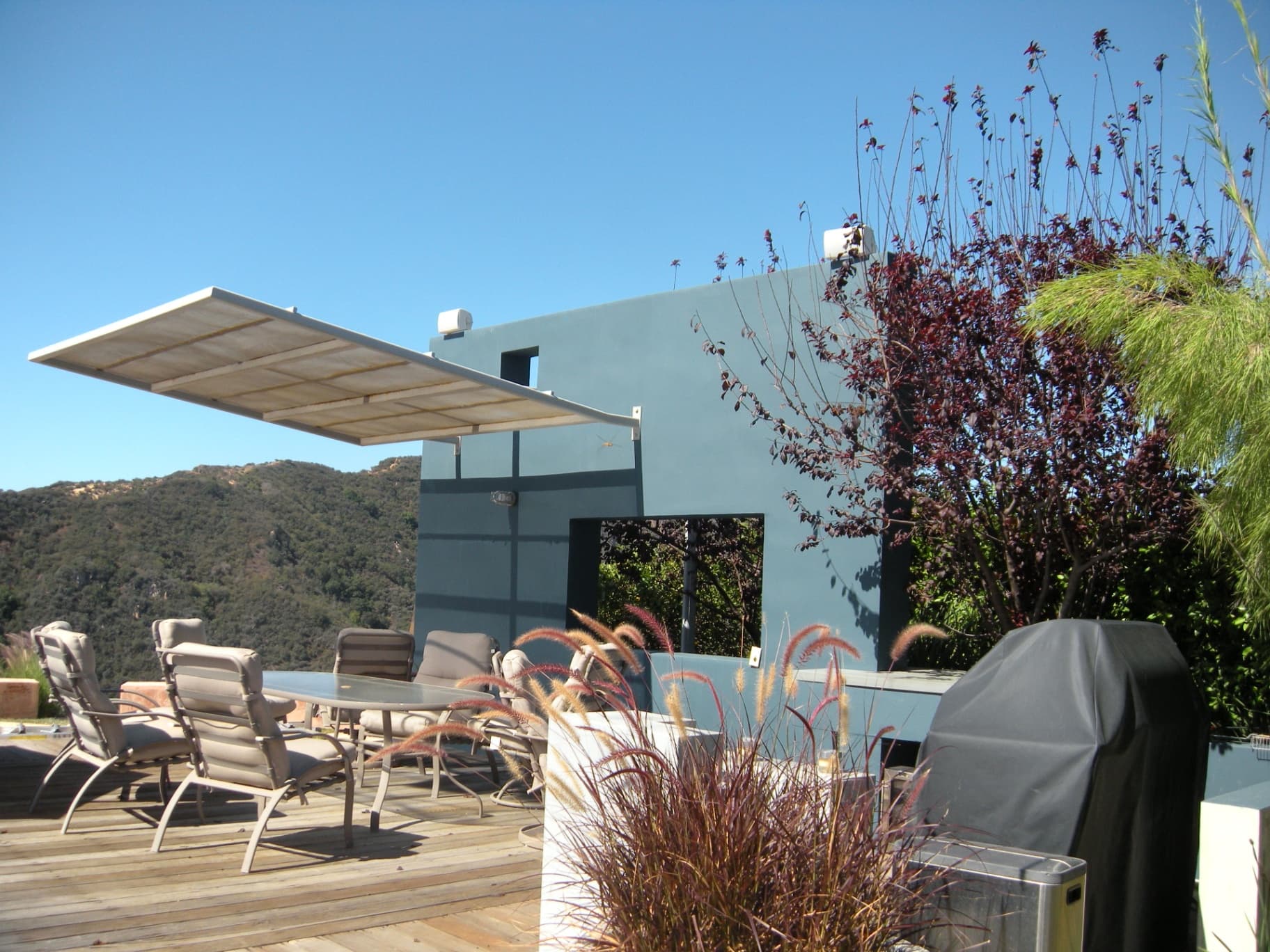 Modern hillside patio with retractable shade awning and discreet outdoor speakers overlooking mountain views