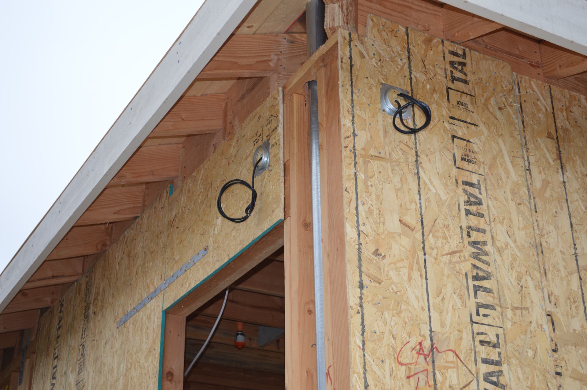 Exterior soffit prewire with round junction boxes and loops of black cable ready for cameras or lights