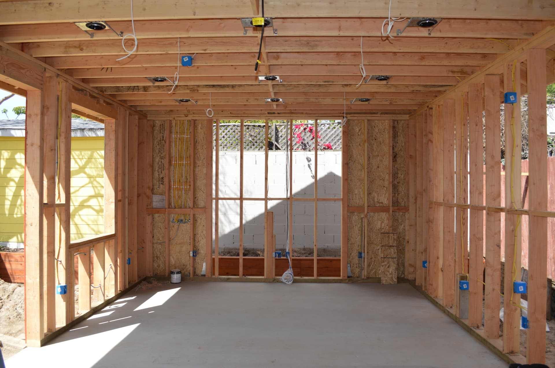 Long framed room with ceiling cans and electrical boxes prewired before drywall installation