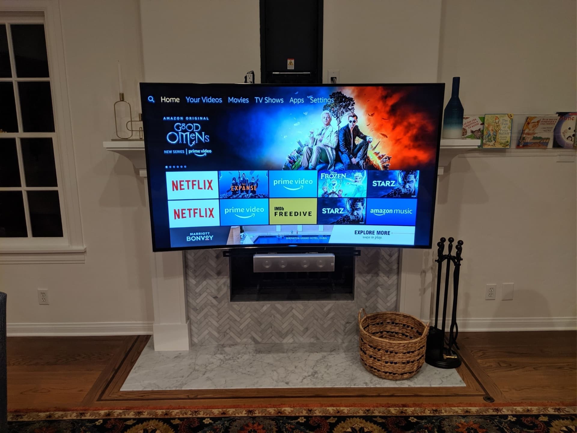 Large TV mounted on marble fireplace with streaming apps and soundbar in elegant living room